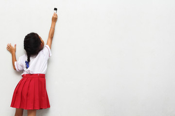 little girl with paintbrush on wall, back view
