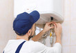 © Africa Studio - Plumber installing water heater in bathroom