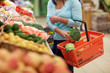 woman with basket buying broccoli at grocery store