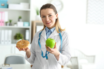 Wall Mural - Young female nutritionist standing with food in her office