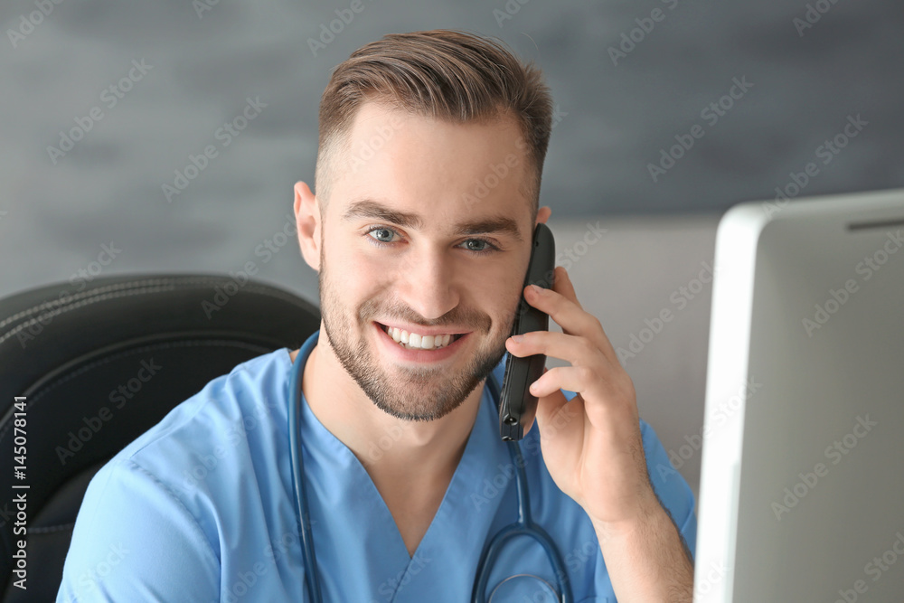 Young medical assistant talking by telephone while working in office