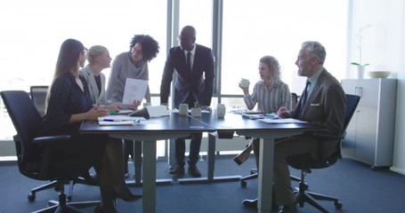 Wall Mural - Group of diverse business people in formal clothing inside their office discussing or looking at information on a laptop computer