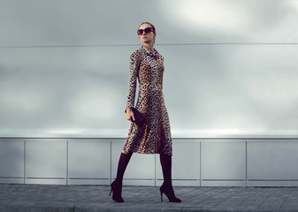 Wall Mural - Fashion woman model wearing a leopard dress is walking in a evening city