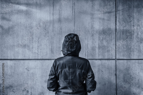 Fotografía Unrecognizable hooded female person facing concrete wall as insu