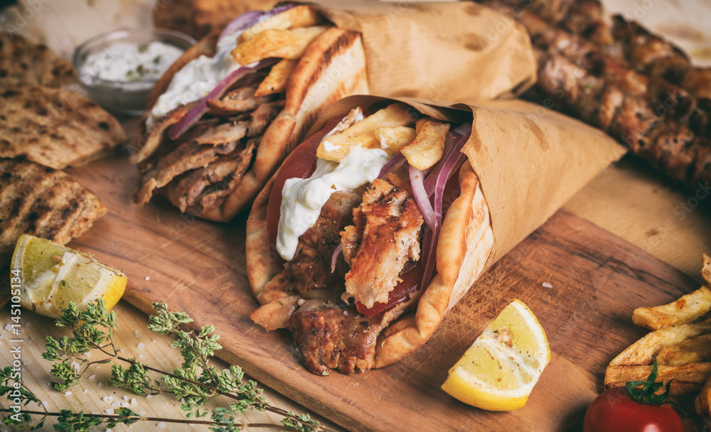 Greek gyros wrapped in pita breads on a wooden table - obrazy, fototapety, plakaty 