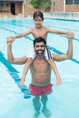 Father carrying son on shoulder in pool