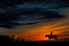 A Silhouette Of A Woman Riding A Horse At Sunset