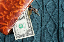 A Brown Leather Purse And A One Dollar Bill, On A Gray Background Of Large Matings
