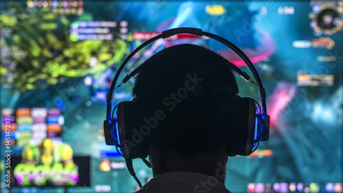 Young gamer playing video game wearing headphone. Canvas Print