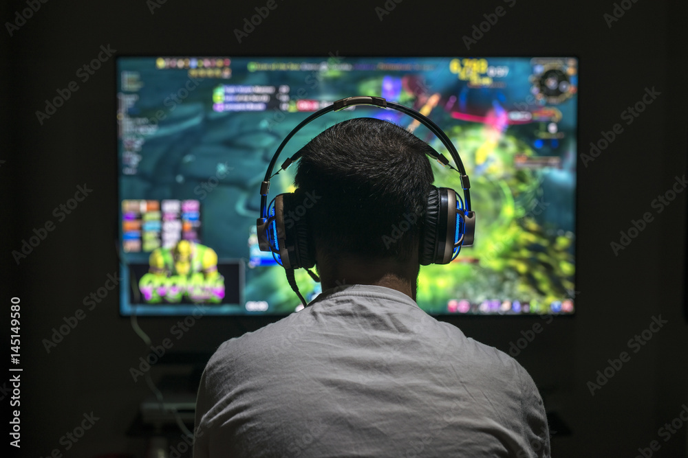 Young gamer playing video game wearing headphone. - obrazy, fototapety, plakaty 