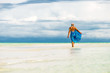 Rear view of blonde woman in blue sarong playful in turquoise water.Copy space