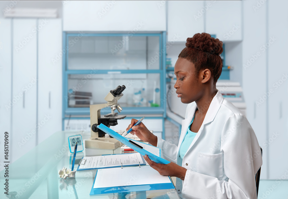 African-american biologist checks records in scientific lab or research facility - obrazy, fototapety, plakaty 