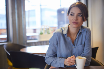 Canvas Print - A young woman having coffee in office