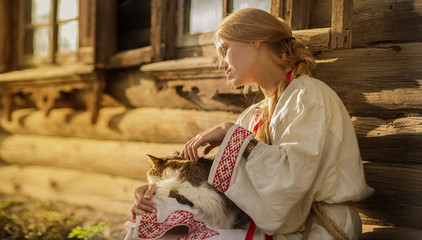 Wall Mural - russian woman with a cat near old wooden house in a village