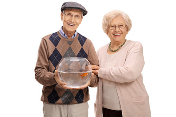 Joyful mature couple with a goldfish in a bowl