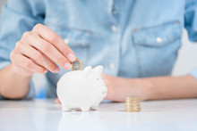 Woman Inserting Coin In Piggybank Showing Save Money Concept