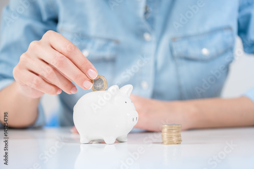 Fotografía Woman Inserting Coin In Piggybank Showing Save Money Concept