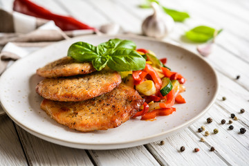 Wall Mural - Fried pork fillets served with steamed zucchini, red bell pepper and garlic