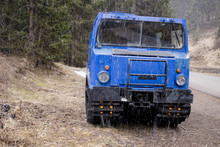 Small Snowcat With Second Wagon Attached To The Trailer Coupling, Electric Blue, Used To Transport People In Mountain Huts, Photographed In Early Spring, During Snowfall, Trentino Alto Adige,  Italia