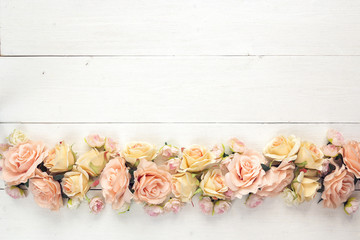 Wall Mural - Border of roses on a white wooden background with empty space for text.