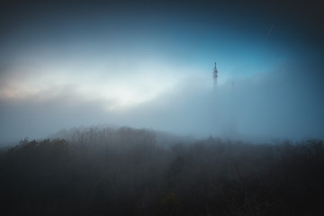 Wall Mural - Misty fog over connection and radio tower in the mountain