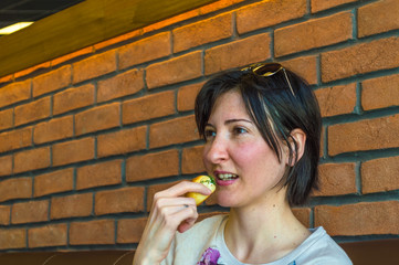 Young brunette woman with short hair eating some pastry