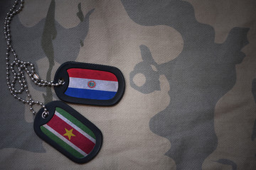 army blank, dog tag with flag of paraguay and suriname on the khaki texture background. military concept