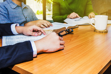 Wall Mural - Christian business man and women reading bible in the office,  hand on burred open bible on wooden table, Christian concept or background