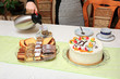 Tort urodzinowy i ciasta, nalewanie herbaty do filiżanki.