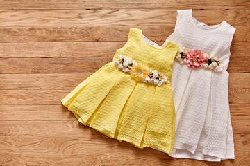 Two beautiful dress for little girls on wooden background.