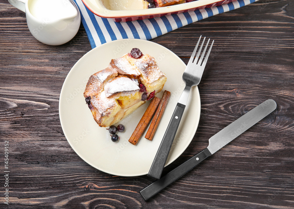Plate with piece of delicious bread pudding on wooden table