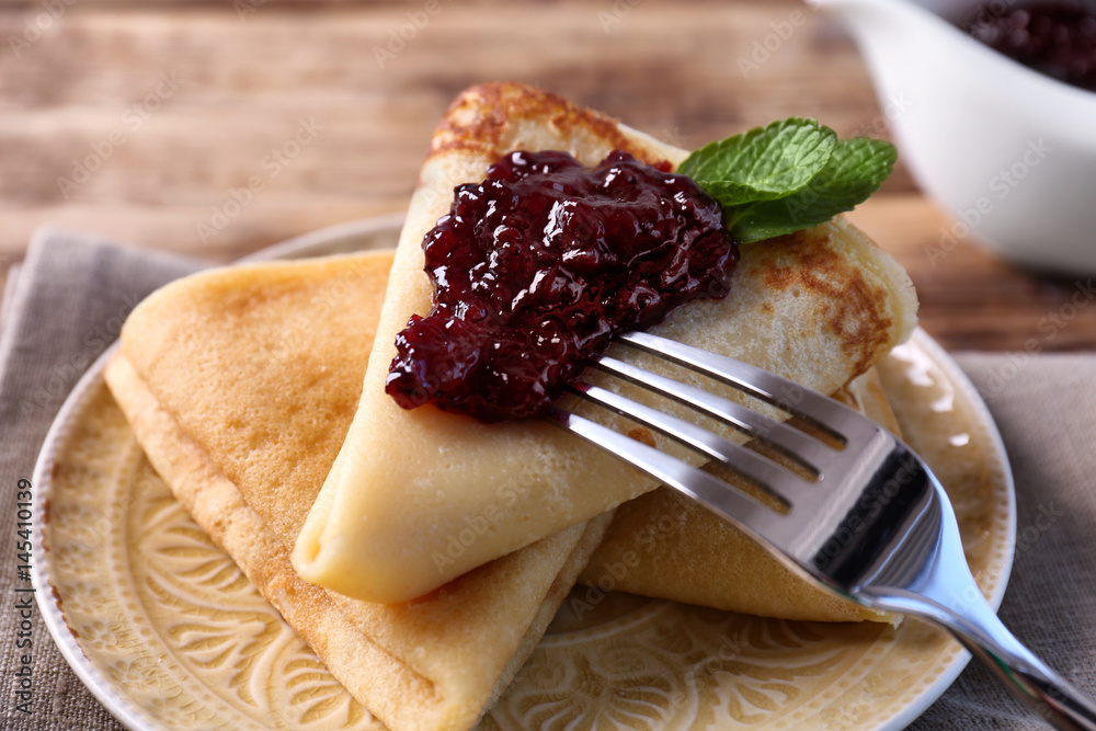 Plate with delicious pancakes and berry jam on table
