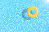 yellow swimming pool ring float in blue water. concept color summer.