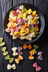 Wall Mural - Beautiful Italian uncooked colored farfalle pasta close-up. Vertical top view