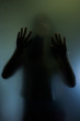 © aradaphotography - Trapped woman concept with back silhouette of hands behind matte glass