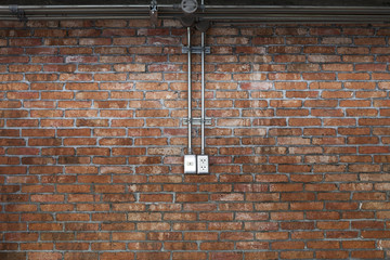 Steel pipe electric wire and plug on vintage brick wall background.