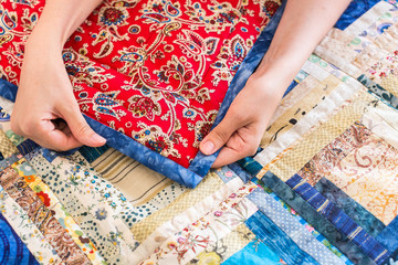 Wall Mural - The caucasian female hand touching a color patchwork quilt with blue and red geometry pattern. Part of Colorful Scrappy blanket close up. dream concept