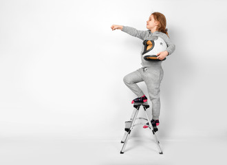 happy child girl dressed in an astronaut costume standing on stepladder