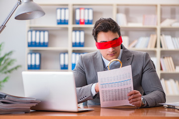 Blindfold businessman sitting at desk in office