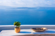 A pot with flower and a plate on a wooden table with ocean background, Santorini, Greece