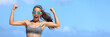 Strong fitness woman banner crop with copyspace on sky. Girl in sunglasses showing off muscular arms flexing biceps for fun on beach. Weight loss success concept.