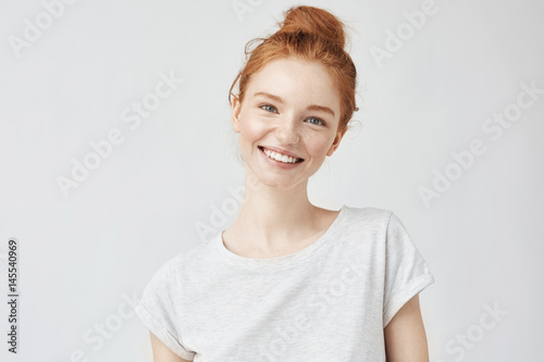 Fotografia Headshot Portrait of happy ginger girl with freckles smiling looking at camera