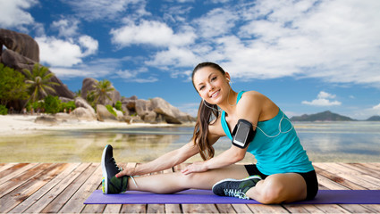 Canvas Print - woman with smartphone stretching leg on mat