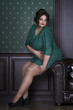 Plus size fashion model in green evening dress, fat woman on luxury interior, overweight female body