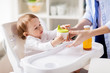 mother giving spout cup with juice to baby at home
