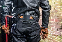 Midsection Rear View Of Gangster With Crowbar And Gun Standing By Brick Wall At Night