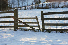 Broken Fence In The Snow At Sunset