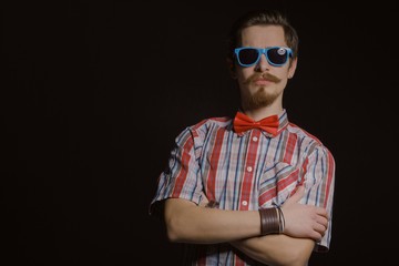 Wall Mural - Young caucasian handsome hipster with beard posing in studio on dark background