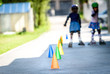 © _jure - Children learning to roller skate on the road with cones.