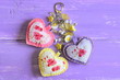 Beautiful hearts and flowers keyring. Handmade felt and fabric keyring or bag charm isolated on lilac wooden background with copy space for text